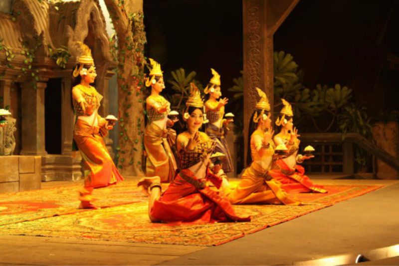 Apsara dance performance with female dancers in ornate costumes performing graceful hand gestures inspired by classical Southeast Asian traditions