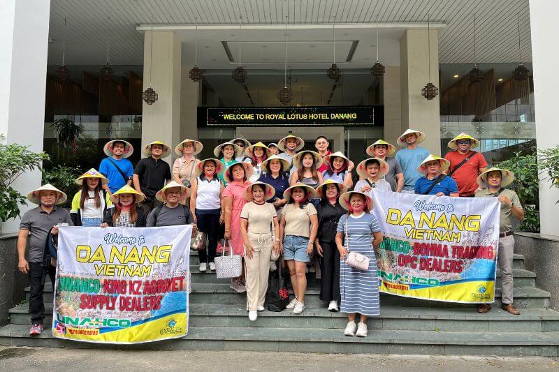 Dong DMC coordinator briefing 40-pax leisure group with color-coded photo pods and partner-branded signage at hotel lobby