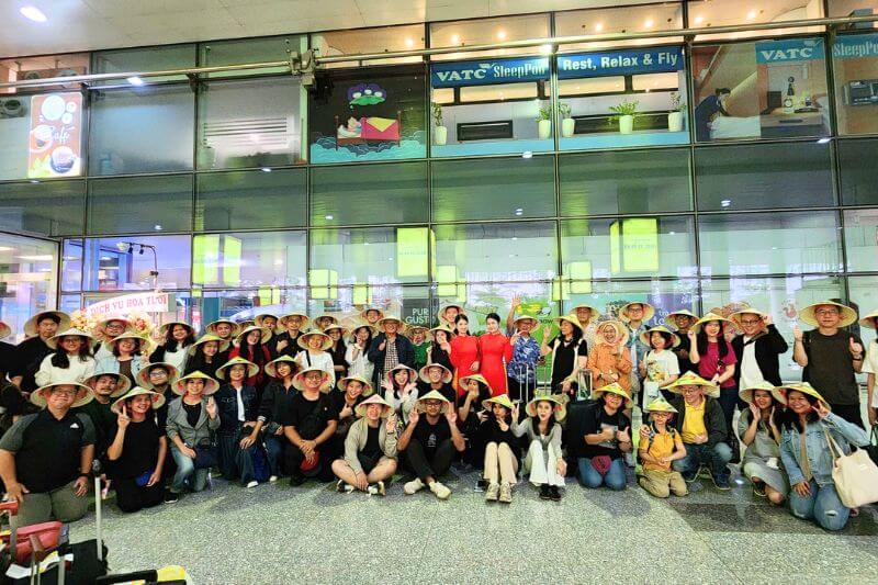 Dong DMC welcome team at Noi Bai Airport with partner-branded signage coordinating a 45-pax leisure group arrival
