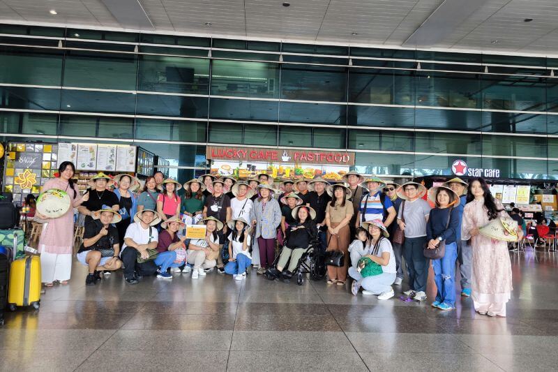 Dong DMC airport welcome team with partner-branded signage and wheelchair-ready assistance for pilgrimage group arrival