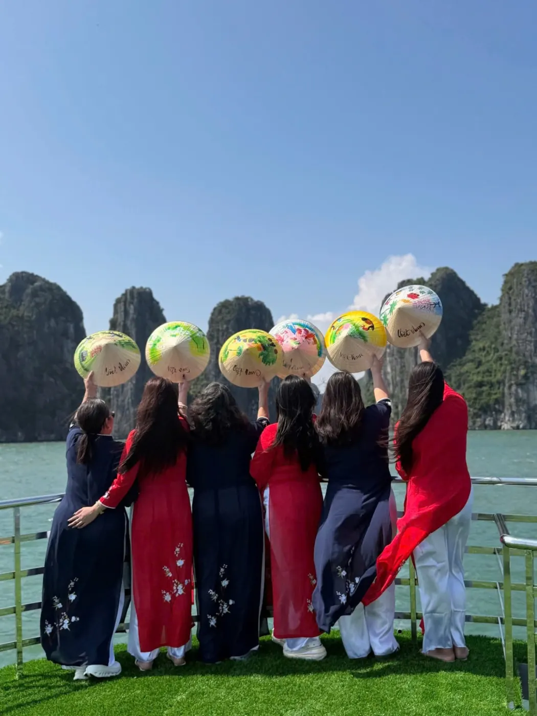 Viajeros filipinos con ao dai en la cubierta de un crucero por la bahía de Halong